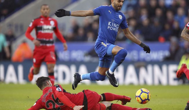 Leicester City&#x27;s Riyad Mahrez, right, and Huddersfield Town&#x27;s Christopher Schindler battle for the ball during their English Premier League soccer match at the King Power Stadium in Leicester, England, Monday Jan. 1, 2018. (Nigel French/PA via AP)