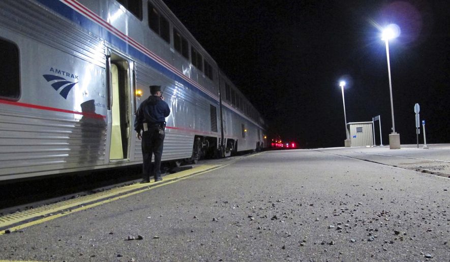 In this Friday, Dec. 29, 2017 photo, an Amtrak employee signals that all passengers are clear as the train departs the Williams Junction station outside Williams, Ariz. Service at the Williams Junction station ended Monday, Jan. 1, 2018. Passengers now are dropped off and picked up in downtown Flagstaff. (AP Photo/Felicia Fonseca)