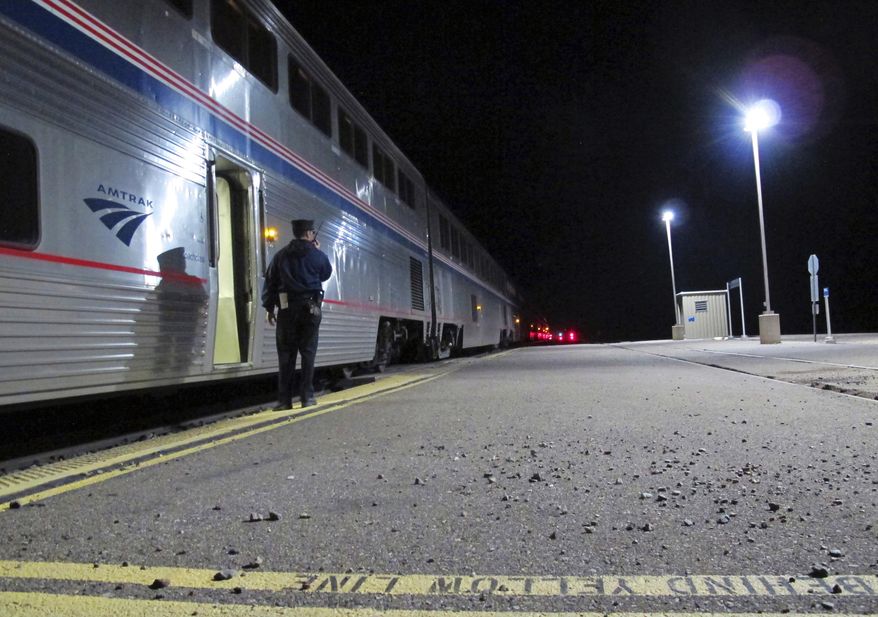 In this Friday, Dec. 29, 2017 photo, an Amtrak employee signals that all passengers are clear as the train departs the Williams Junction station outside Williams, Ariz. Service at the Williams Junction station ended Monday, Jan. 1, 2018. Passengers now are dropped off and picked up in downtown Flagstaff. (AP Photo/Felicia Fonseca)