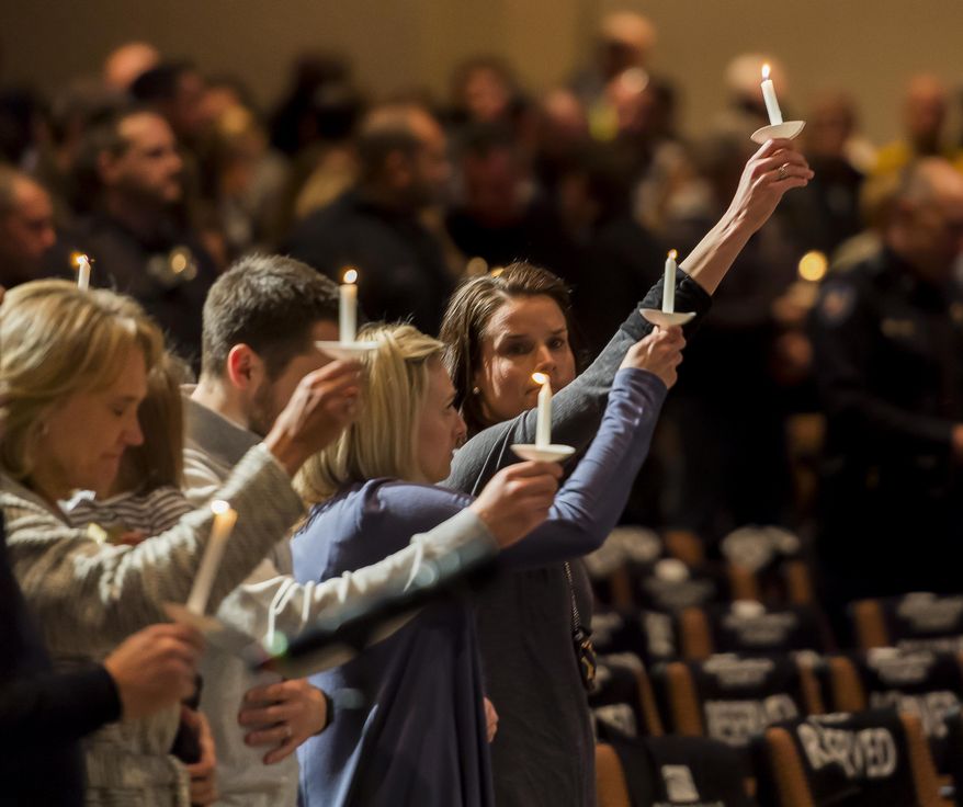 Gracie Parrish, center, holds a candle for her late husband Zackari Parrish, a Douglas County deputy, at Mission Hills Church in Littleton, Colo., Monday, Jan. 1, 2018. A man who shot and killed the Colorado deputy and wounded several others along with a few civilians was an attorney and an Iraq war veteran who had posted videos online in recent months criticizing professors and law enforcement officials, authorities said Monday. (Dougal Brownlie/The Gazette via AP)