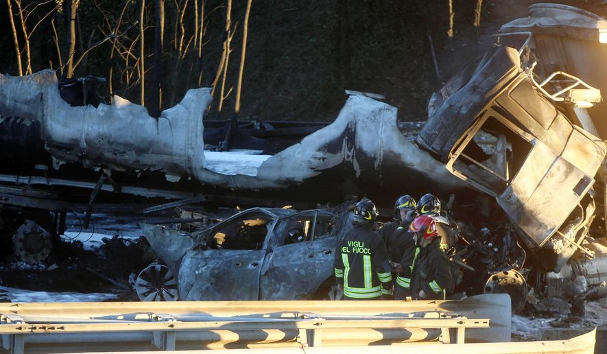 Firefighters look at the charred vehicles after, according to reports, a tanker truck carrying inflammable liquid went ablaze and caused the death of five passengers in a car and the driver of the truck behind it, along the A21 motorway between Brescia and Turin, in northern Italy, Tuesday, Jan. 2, 2018. RAI state TV said traffic on the A21 had slowed because of a previous accident, when a truck laden with sand struck the car in front of it, which in turn slammed into the tanker truck. (Filippo Venezia/ANSA via AP)