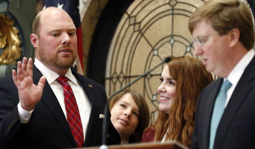 Senator-elect Joel Carter, R-Harrison County, left, recites his oath of office as administered by Republican Lt. Gov. Tate Reeves, right, as his son, Joel R. Carter III, second from left, and his wife, Suzanne Carter, watch, prior to the lawmakers' roll call being announced, in Senate Chambers at the Capitol in Jackson, Miss., Tuesday, Jan. 2, 2018. (AP Photo by Rogelio V. Solis)