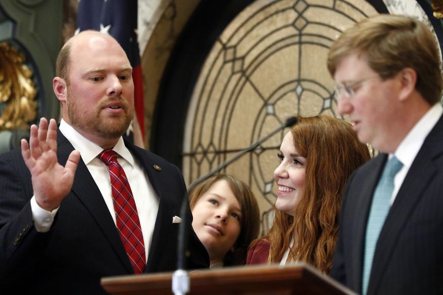 Senator-elect Joel Carter, R-Harrison County, left, recites his oath of office as administered by Republican Lt. Gov. Tate Reeves, right, as his son, Joel R. Carter III, second from left, and his wife, Suzanne Carter, watch, prior to the lawmakers' roll call being announced, in Senate Chambers at the Capitol in Jackson, Miss., Tuesday, Jan. 2, 2018. (AP Photo by Rogelio V. Solis)