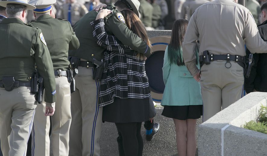 FILE - In this Dec. 27, 2017 file photo, Rosanna Camilleri, right, the wife of late California Highway Patrol Officer Andrew Camilleri Sr., hugs CHP officer Jonathan Velazquez following a bell ringing ceremony held at the highway patrol academy in West Sacramento, Calif. Authorities say a 22-year-old man who killed Camilleri Sr. on Christmas Eve after he slammed his car into the back of the officer's parked patrol car has been charged with second-degree murder. Alameda County District Attorney Nancy O'Malley on Tuesday, Jan. 2, 2018, identified Mohammed Ali, of Hayward, as the driver of a speeding Cadillac that drifted off Interstate 880 and crashed against Officer Andrew Camilleri's patrol SUV. (AP Photo/Rich Pedroncelli, File)