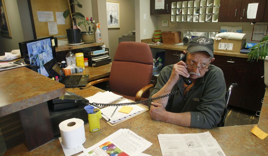 In this Friday, Dec. 29, 2017 photo, Dan Collins eyes the front door while answering a phone at the front desk of the COMEA House homeless shelter, in Cheyenne, Wyo. Collins, a recovering alcoholic and double leg amputee, is now working at the shelter. (Jacob Byk /The Wyoming Tribune Eagle via AP)