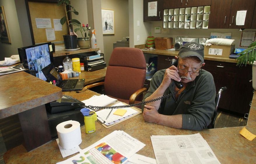 In this Friday, Dec. 29, 2017 photo, Dan Collins eyes the front door while answering a phone at the front desk of the COMEA House homeless shelter, in Cheyenne, Wyo. Collins, a recovering alcoholic and double leg amputee, is now working at the shelter. (Jacob Byk /The Wyoming Tribune Eagle via AP)