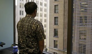 FILE - In this Sept. 22, 2016, file photo, Sorihin, who uses one name, one of two Indonesian fisherman who escaped slavery aboard a U.S.-flagged tuna and swordfish vessel when it docked at San Francisco&#39;s Fisherman&#39;s Wharf, looks out toward Montgomery Street at the offices of the Legal Aid Society in San Francisco. Attorneys for Sorihin and Abdul Fatah told The Associated Press on Wednesday, Jan. 3, 2018, that they settled their lawsuit against Thoai Van Nguyen, the California-based owner and captain of the Sea Queen II. (AP Photo/Eric Risberg, File)