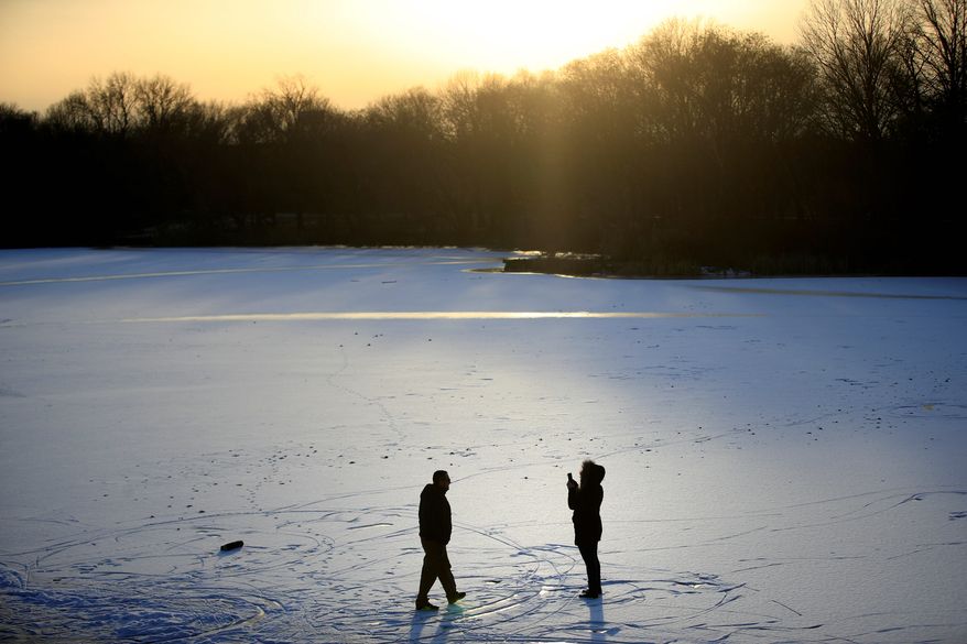 A couple takes photographs on a frozen pond at Franklin Delano Roosevelt Park in Philadelphia, Wednesday, Jan. 3, 2018. (AP Photo/Matt Rourke)