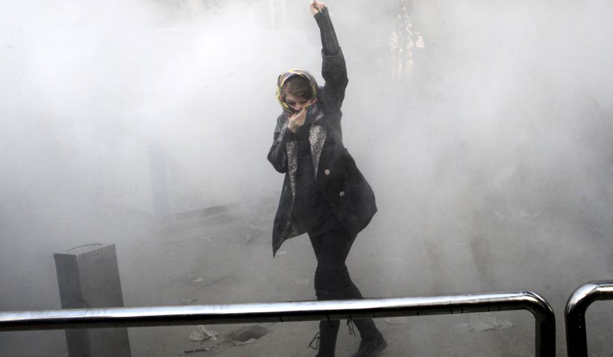 In this Saturday, Dec. 30, 2017, photo, taken by an individual not employed by the Associated Press and obtained by the AP outside Iran, a university student attends a protest inside Tehran University while a smoke grenade is thrown by anti-riot Iranian police, in Tehran, Iran. Iran&#x27;s top regional foes, Israel and Saudi Arabia, are both watching that country&#x27;s protests for signs they could lead to change. Iran&#x27;s supreme leader has accused enemies of stoking the unrest. (Associated Press)