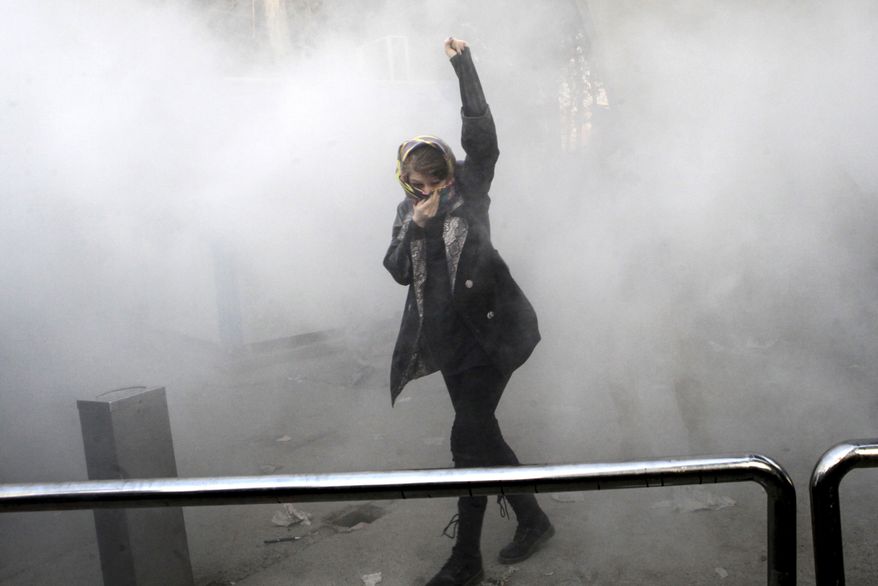 In this Saturday, Dec. 30, 2017, photo, taken by an individual not employed by the Associated Press and obtained by the AP outside Iran, a university student attends a protest inside Tehran University while a smoke grenade is thrown by anti-riot Iranian police, in Tehran, Iran. Iran&#39;s top regional foes, Israel and Saudi Arabia, are both watching that country&#39;s protests for signs they could lead to change. Iran&#39;s supreme leader has accused enemies of stoking the unrest. (Associated Press)