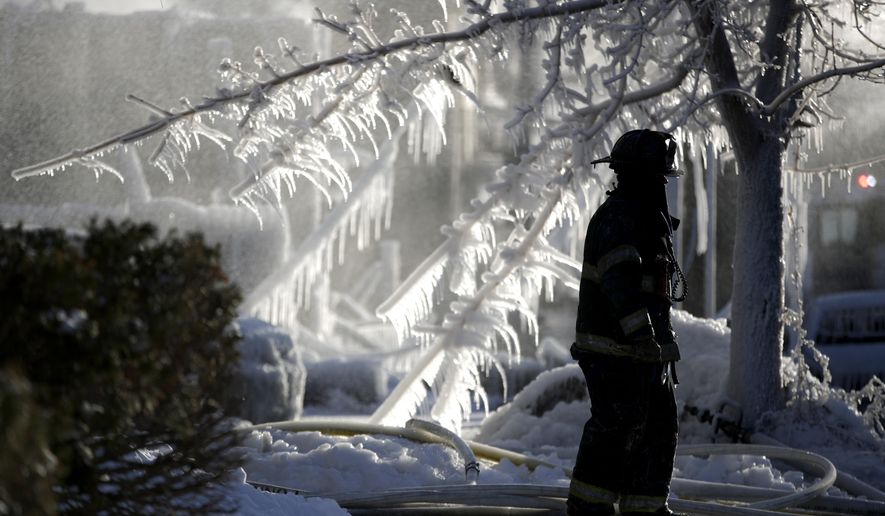 A Newark firefighter walks near the site of a fire, Friday, Jan. 5, 2018, in Newark, N.J. The fire broke out in a vacant structure in Newark early Friday morning in the area of 9th Avenue and South 14th Street and spread to two adjacent structures. Gusty winds carried the flames to two buildings across the street. (AP Photo/Julio Cortez)