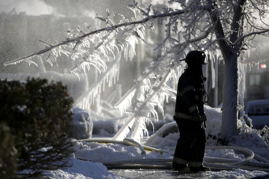A Newark firefighter walks near the site of a fire, Friday, Jan. 5, 2018, in Newark, N.J. The fire broke out in a vacant structure in Newark early Friday morning in the area of 9th Avenue and South 14th Street and spread to two adjacent structures. Gusty winds carried the flames to two buildings across the street. (AP Photo/Julio Cortez)