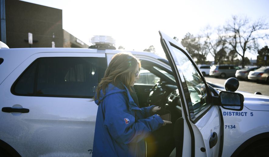 In a Dec. 21, 2017 photo, Samantha Rabins, of Mental Health Center of Denver, prepares to roll out with an officer at Denver Police District 5 in Denver. Faced with escalating arrests in Colorado, the state is prodding police departments to try new diversion programs for those with mental illnesses or drug addictions. Instead of just arresting troubled individuals, police in Boulder and Denver now are having mental health clinicians ride along when police respond to emergency 911 calls. (Aaron Ontiveroz//The Denver Post via AP)