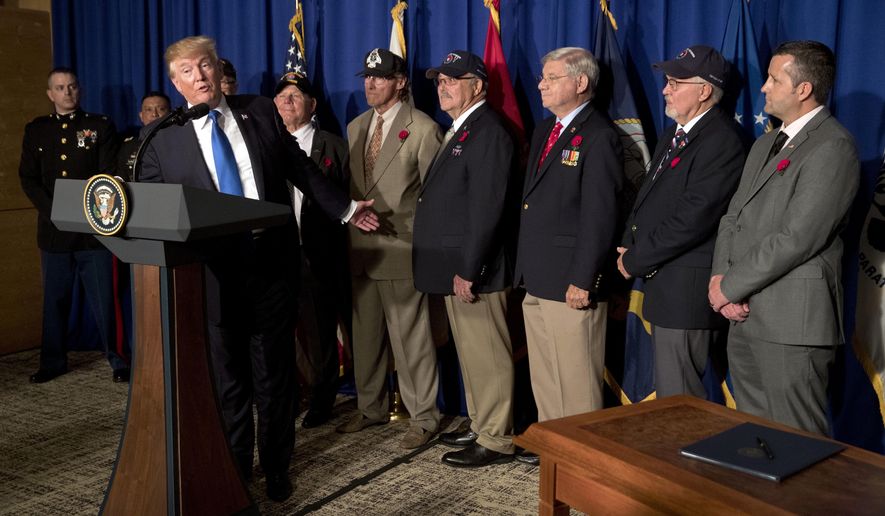 President Donald Trump is flanked by veterans at an event to sign a proclamation honoring veterans at the Hyatt Regency Danang Resort in Danang, Vietnam, on Nov. 10, 2017. (Associated Press) **FILE**
