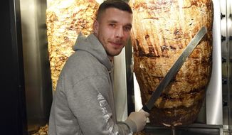 Former Germany soccer player Lukas Podolski stands in a kebab restaurant in Cologne, Germany, Saturday, Jan. 6, 2018. Former Germany, Arsenal and Bayern  Munich star Lukas Podolski has unveiled a new project: a kebab restaurant in his longtime home city of Cologne. News agency dpa reported that Podolski spokesman Sebastian Lange said about 1,000 fans turned up Saturday to the opening of Mangal Doener, some arriving more than five hours early. (Henning Kaiser/dpa via AP)