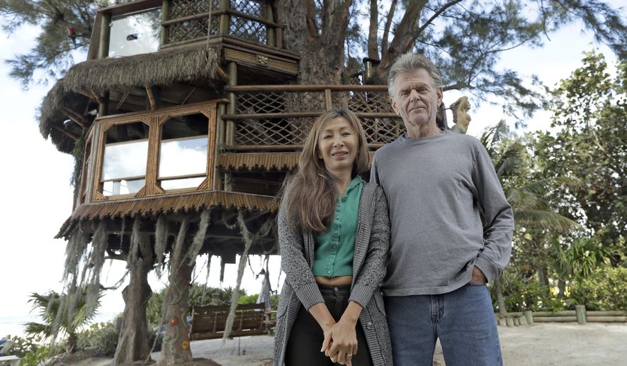 Lynn Tran and her husband Richard Hazen pose near their Australian pine treehouse Thursday, Jan. 4, 2018, in Holmes Beach, Fla. The couple is hoping the U.S. Supreme Court will hear their case after city and state officials ordered the treehouse removed. (AP Photo/Chris O'Meara)
