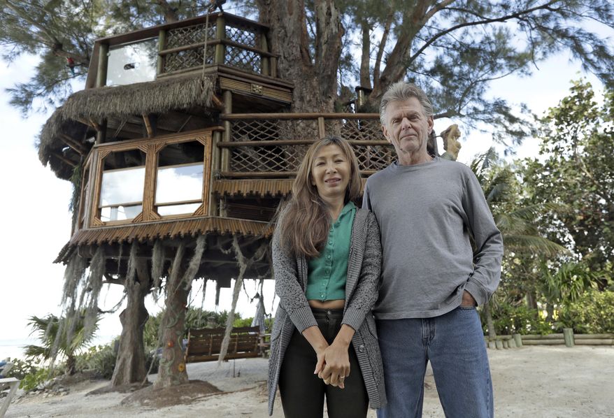 Lynn Tran and her husband Richard Hazen pose near their Australian pine treehouse Thursday, Jan. 4, 2018, in Holmes Beach, Fla. The couple is hoping the U.S. Supreme Court will hear their case after city and state officials ordered the treehouse removed. (AP Photo/Chris O'Meara)