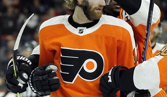 Philadelphia Flyers&#39; Sean Couturier gets a pat on the helmet from teammate Wayne Simmonds after scoring a goal during the second period of an NHL hockey game against the Buffalo Sabres, Sunday, Jan. 7, 2018, in Philadelphia. (AP Photo/Tom Mihalek)