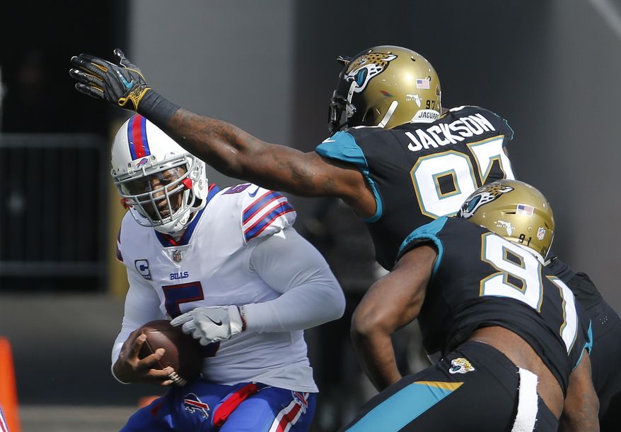 Buffalo Bills quarterback Tyrod Taylor, left, is sacked by Jacksonville Jaguars defensive tackle Malik Jackson, center, and defensive end Yannick Ngakoue (91) in the first half of an NFL wild-card playoff football game, Sunday, Jan. 7, 2018, in Jacksonville, Fla. (AP Photo/Stephen B. Morton)