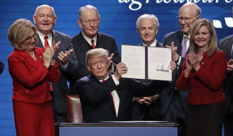 In this file photo, President Donald Trump holds up an executive order after signing it at the American Farm Bureau Federation annual convention Monday, Jan. 8, 2018, in Nashville, Tenn., as, from left, Rep. Diane Black, R-Tenn., Agriculture Secretary Sonny Perdue, Sen. Lamar Alexander, R-Tenn., Sen. Bob Corker, R-Tenn., Sen. Pat Roberts, R-Kan., and Rep. Marsha Blackburn, R-Tenn., applaud. Mrs. Blackburn, who is running for the U.S. Senate, will welcome Mr. Trump at a Nashville campaign rally on May 29, 2018. (AP Photo/Mark Humphrey) **FILE**