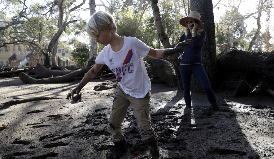 Jennifer Markham, right, and her son Peter walk in mud in Montecito, Calif., Wednesday, Jan. 10, 2018. Dozens of homes were swept away or heavily damaged and several people were killed Tuesday as downpours sent mud and boulders roaring down hills stripped of vegetation by a gigantic wildfire that raged in Southern California last month. (AP Photo/Marcio Jose Sanchez)