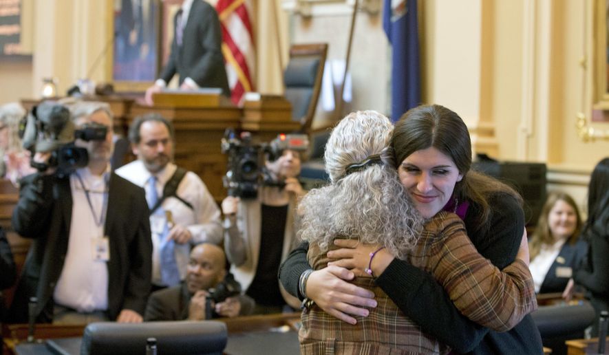 Del. Danica Roem, D-Prince William, right, the first transgender delegate, hugs Del. Cheryl Tuprin, D-Virginia Beach, left, prior to opening ceremonies of the 2018 session of the Virginia House of Delegates at the Capitol in Richmond, Va., Wednesday, Jan. 10, 2018. (AP Photo/Steve Helber)