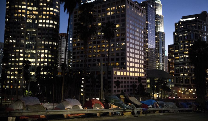 FILE - In this Dec. 1, 2017 file photo, homeless tents are dwarfed by skyscrapers as 63-year-old Vincent, who only gave his first name, sorts his belongings in Los Angeles. President Donald Trump's administration is announcing $2 billion in grants for local programs to deal with homelessness. The funding total is a record for the Continuum of Care grants, but only a small increase over recent years. The announcement comes as the administration is calling for cuts to housing programs and as the West Coast is dealing with a homeless crisis. (AP Photo/Jae C. Hong, File)