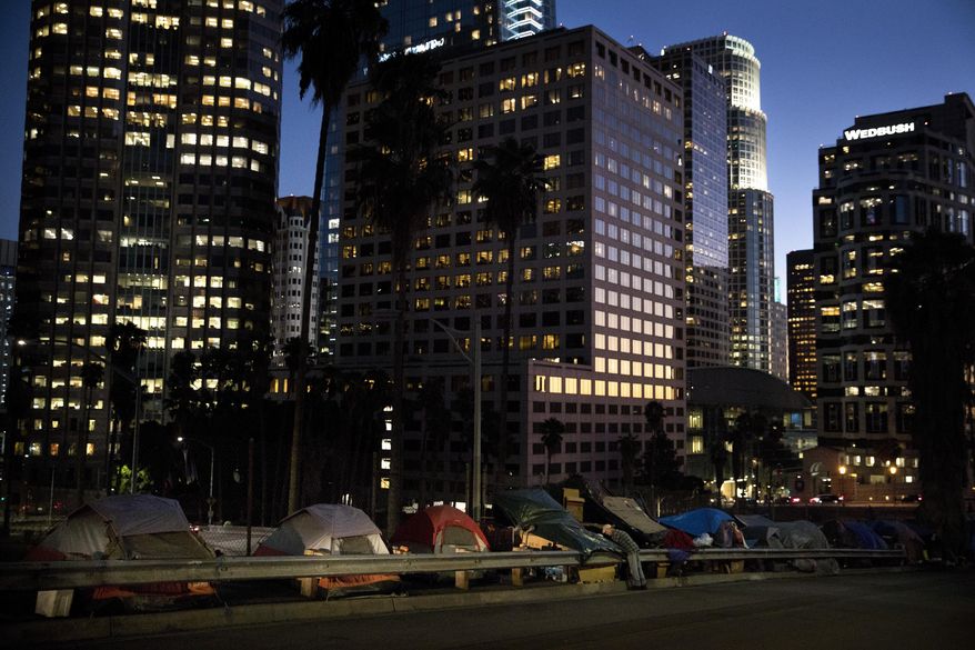 FILE - In this Dec. 1, 2017 file photo, homeless tents are dwarfed by skyscrapers as 63-year-old Vincent, who only gave his first name, sorts his belongings in Los Angeles. President Donald Trump's administration is announcing $2 billion in grants for local programs to deal with homelessness. The funding total is a record for the Continuum of Care grants, but only a small increase over recent years. The announcement comes as the administration is calling for cuts to housing programs and as the West Coast is dealing with a homeless crisis. (AP Photo/Jae C. Hong, File)