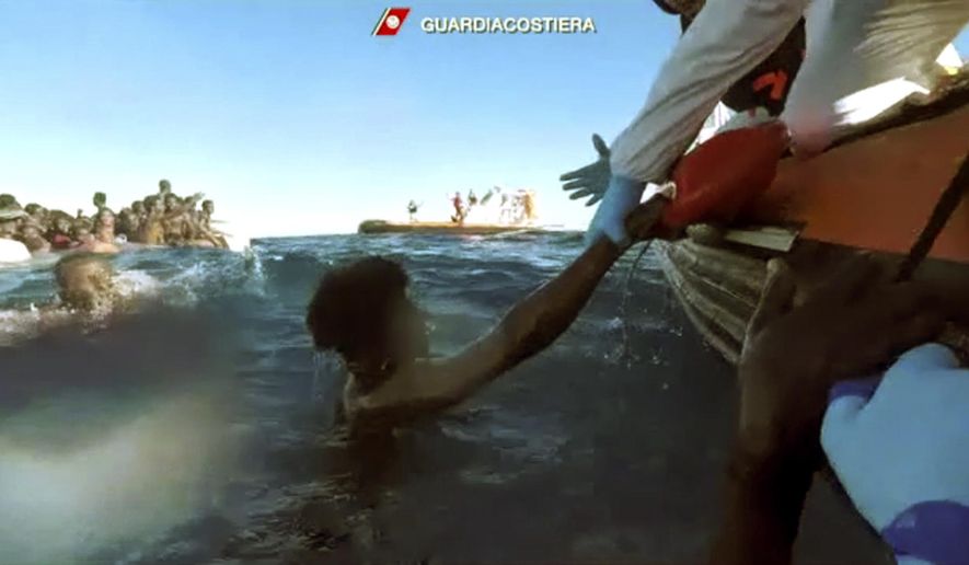 This frame of a video taken by the Italian Coast Guard on Jan. 6, 2018, in the Mediterranean Sea off Libya, shows migrants being rescued from dinghies as they try to cross to Italy. As many as 64 African migrants, including a mother whose surviving 3-year-old child desperately clung to her, are feared dead after a traffickers’ overcrowded rubber dinghy from Libya started taking on water and deflating in the Mediterranean Sea. (Italian Coast Guard via Ap Photo)