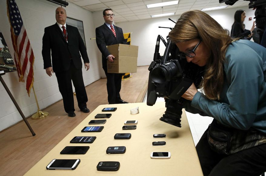 A television news photographer films confiscated cell phones as officials prepare to return them to a box of evidence following a news conference at Jessup Correctional Institution in Jessup, Md., Thursday, Jan. 11, 2018. Maryland Gov. Larry Hogan and State Prosecutor Emmet Davitt announced indictments against two of the prison's corrections officers for allegedly attempting to smuggle in contraband for inmates that included drugs and cell phones. (AP Photo/Patrick Semansky)