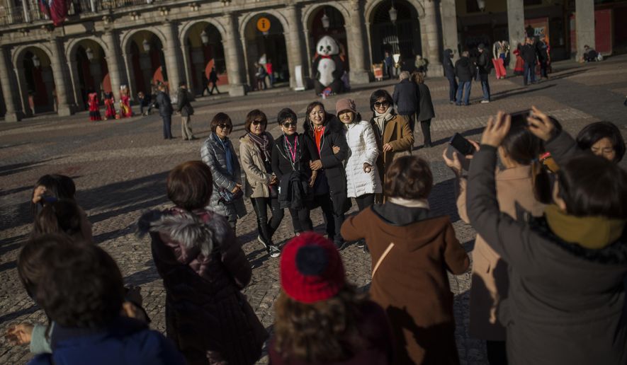 Tourists pose for a photograph at the Mayor square in central Madrid, Thursday, Jan. 11, 2018. Spain says it has broken its record of international visitors for the fifth consecutive year in 2017 with 82 million tourists that chose restive Catalonia as their main Spanish destination. (AP Photo/Francisco Seco)