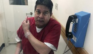FILE - In this Nov. 17, 2017, file photo, escaped hospital patient Randall Saito points to a guard as he sits in an inmate visitor&#39;s booth at San Joaquin County Jail before a scheduled court hearing in French Camp, Calif. Court documents say Saito, who escaped from a Hawaii psychiatric hospital and flew to California, was caught with two high-quality fake IDs, two cellphones and more than $6,000 in cash.  (AP Photo/Terry Chea, File)