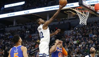 Minnesota Timberwolves&#39; Andrew Wiggins, center, lays up a shot as New York Knicks&#39; Courtney Lee, left, and Enes Kanter, of Turkey, watch in the first half of an NBA basketball game Friday, Jan. 12, 2018, in Minneapolis. (AP Photo/Jim Mone)