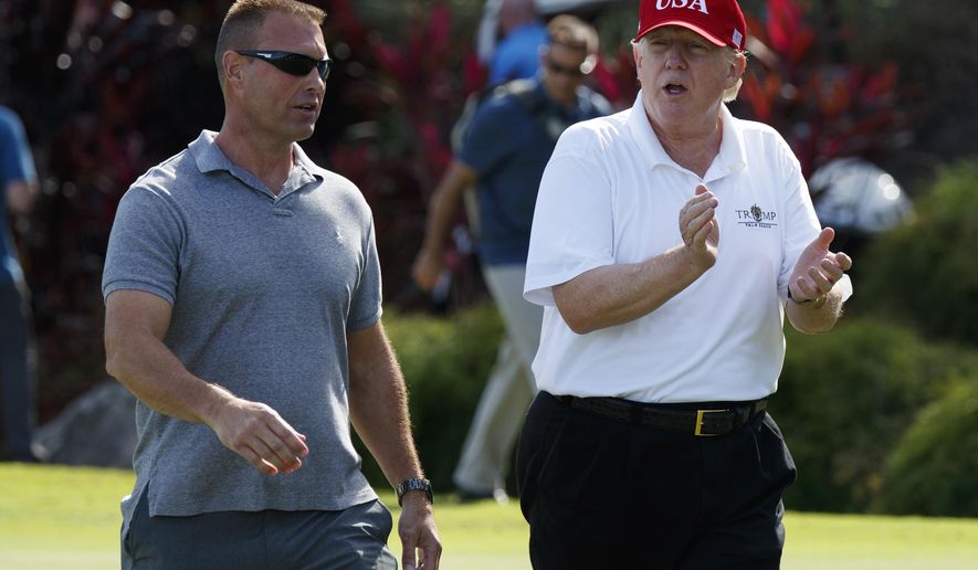 FILE - In this Friday, Dec. 29, 2017 file photo, President Donald Trump walks with Gene Gibson, commanding officer at Coast Guard Station Lake Worth Inlet, as he arrives to meet with members of the U.S. Coast Guard, who he invited to play golf, at Trump International Golf Club, in West Palm Beach, Fla. Trump will be the patient, not the commander in chief offering comfort, when he visits the Walter Reed military hospital. Trump heads to the medical facility in the Maryland suburbs of Washington on Friday, Jan. 12, 2018, for his first medical check-up as president. (AP Photo/Evan Vucci, File)