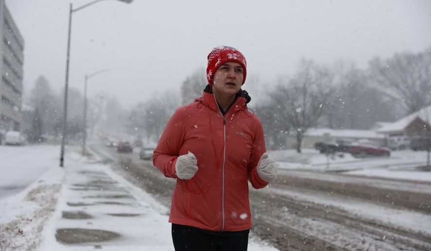 Carlie Glaze runs along Second Street during a snowstorm, Friday, Jan. 12, 2018 in Bloomington, Ind. Glaze said she&#x27;s walked in the snow earlier and it wasn&#x27;t too slick so she had the urge to take a run in the snow while she still could do so. (Jeremy Hogan/The Herald-Times via AP)