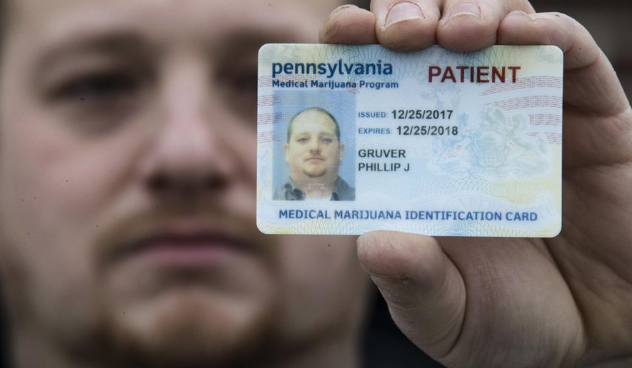 In this Wednesday, Jan. 10, 2018 photo Phil Gruver poses for a photograph with his Pennsylvania with his medical marijuana card in Emmaus, Pa. As gun-loving Pennsylvania becomes the latest state to operate a medical marijuana program, with the first dispensary on track to begin sales next month, authorities are warning patients that federal law bars marijuana users from having guns or ammunition. Gruver is weighing what to do with his .22-caliber rifle and a handgun he keeps for home defense. (AP Photo/Matt Rourke)
