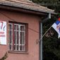A Serbian flag and a picture of assassined Kosovo Serb politician Oliver Ivanovic are seen on his office in the northern, Serb-dominated part of Mitrovica, Kosovo, Tuesday, Jan. 16, 2018. Ivanovic was shot and killed Tuesday morning, raising ethnic tensions in the region and halting EU-mediated talks between Kosovo and Serbia on the day they were due to resume. (AP Photo/Bojan Slavkovic)