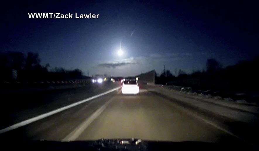 In this late Tuesday, Jan. 16, 2018, image made from dashcam video, a brightly lit object falls from the sky above a highway in the southern Michigan skyline. (Zack Lawler/WWMT via AP)