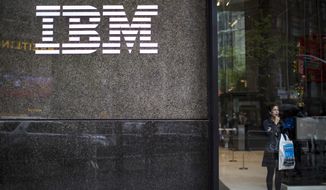 In this Wednesday, April 26, 2017, photo, a woman looks out from the lobby next to the logo displayed on the IBM Building in New York. On Thursday, Jan. 18, 2018, IBM Corp. reports financial results. (AP Photo/Mary Altaffer)