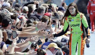 FILE - In this Feb. 22, 2015, file photo, driver Danica Patrick greets fans as she is introduced before the start of the Daytona 500 NASCAR Sprint Cup series auto race at Daytona International Speedway in Daytona Beach, Fla. GoDaddy tells The Associated Press it is partnering with Patrick as she closes her career with the Daytona 500 and the Indianapolis 500. (AP Photo/John Raoux, File) **FILE**