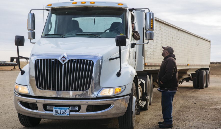 In this Dec. 21, 2017 photo, Bob Worth's son, John Worth, right, talks with another employee on the family farm while loading trucks with corn just outside of Lake Benton, Minn. Worth, whose family has farmed in western Minnesota for generations, is familiar with the pressures that can make modern farming stressful. (Evan Frost/Minnesota Public Radio via AP)