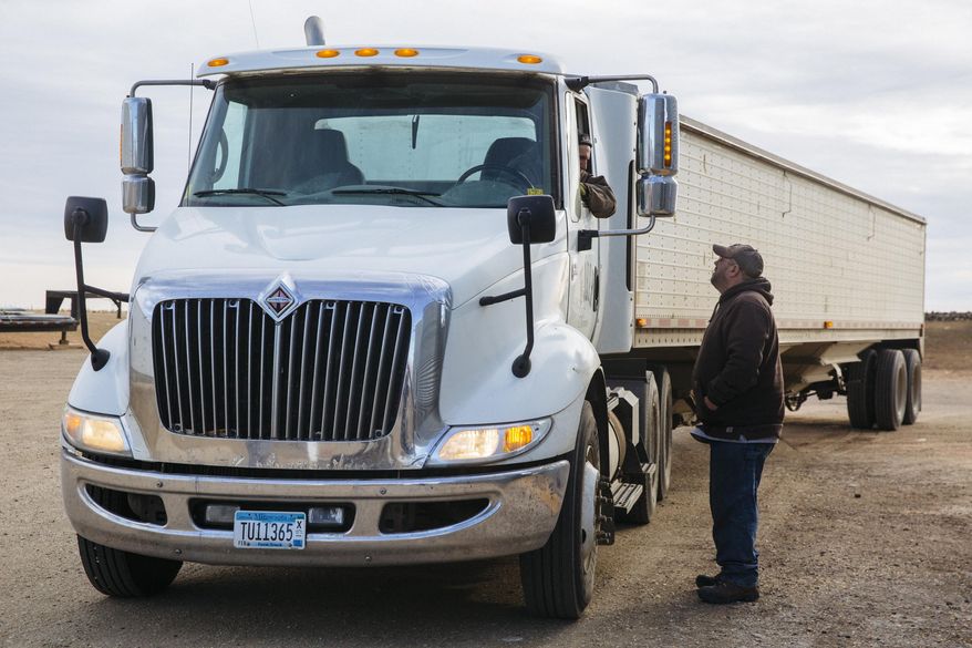 In this Dec. 21, 2017 photo, Bob Worth's son, John Worth, right, talks with another employee on the family farm while loading trucks with corn just outside of Lake Benton, Minn. Worth, whose family has farmed in western Minnesota for generations, is familiar with the pressures that can make modern farming stressful. (Evan Frost/Minnesota Public Radio via AP)