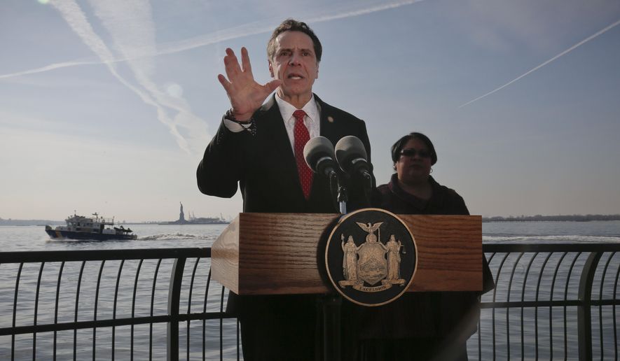 New York Gov. Andrew Cuomo, center, holds a press conference with the Statue of Liberty in the distance behind him, Sunday Jan. 21, 2018, in New York. Cuomo says the statue and Ellis Island will be open for visitors on Monday, with New York state picking up the tab for federal workers. The two sites have been closed due to the federal government shutdown. (AP Photo/Bebeto Matthews)