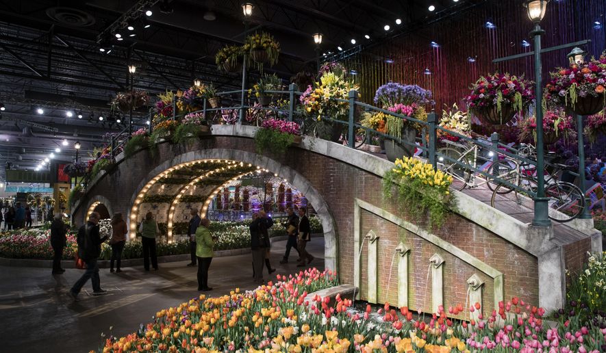 FILE - In this March 10, 2017, file photo, visitors view horticultural displays during a preview of the annual Philadelphia Flower Show, featuring the theme "Holland: Flowering the World," at the Pennsylvania Convention Center in Philadelphia. As the East Coast slogs through chilly temperatures and winter dreariness, visitors will dive into spring during the annual Philadelphia Flower Show from March 3 to 11, 2018, featuring the theme "Wonders of Water" and promising to "celebrate the beauty and life-sustaining interplay of horticulture and water." (AP Photo/Matt Rourke, File)