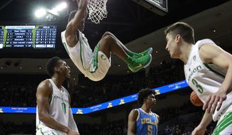 Oregon&#39;s Victor Bailey Jr. hangs from the rim after a dunk over UCLA&#39;s Chris Smith, center bottom, while teammates Troy Brown Jr., left and Payton Pritchard, right, celebrate during the first half of an NCAA college basketball game Saturday, Jan. 20, 2018, in Eugene, Ore. (AP Photo/Chris Pietsch)