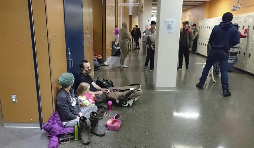Evacuees gather at Kodiak High School in Kodiak, Alaska, Tuesday, Jan 23, 2018, after an earthquake and tsunami alert. A powerful undersea earthquake sent Alaskans fumbling for suitcases and racing to evacuation centers in the middle of the night Tuesday after a cellphone alert warned that a tsunami could smash into the state's southern coast and western Canada. (Grigore Ciubotaru via AP)