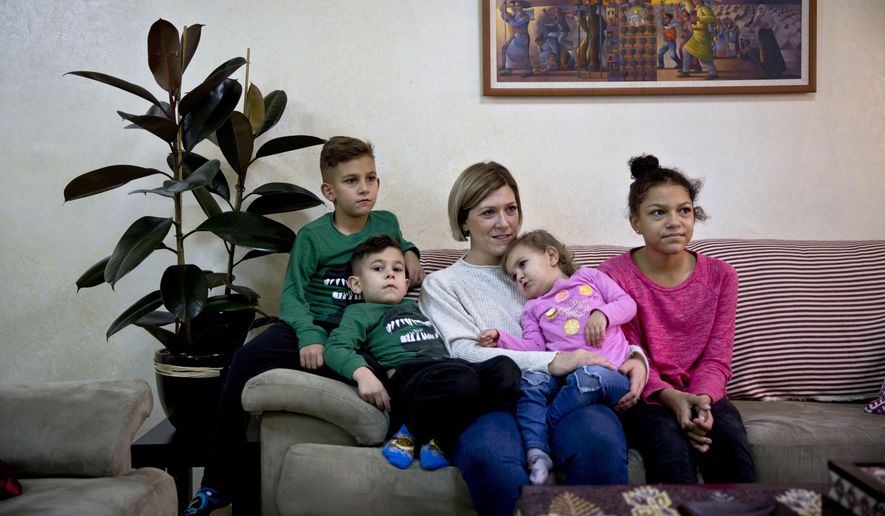 In this Wednesday, Jan. 10, 2018 photo, Kate Hamad, originally from Grimes, Iowa, sits with her children during an interview with The Associated Press in Ramallah, West Bank. Hamad doesn't dare leave Ramallah, fearing deportation if stopped at an Israeli checkpoint on the outskirts of the autonomous Palestinian city. Activists say Israel is making it harder for foreigners with ties to Palestinians to stay in the West Bank legally, rejecting more visa requests or issuing them for shorter period. Israel denies it’s adopted tougher rules. (AP Photo/Majdi Mohammed)