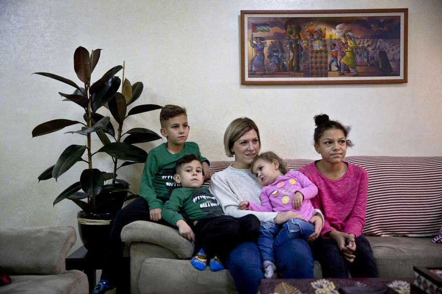 In this Wednesday, Jan. 10, 2018 photo, Kate Hamad, originally from Grimes, Iowa, sits with her children during an interview with The Associated Press in Ramallah, West Bank. Hamad doesn't dare leave Ramallah, fearing deportation if stopped at an Israeli checkpoint on the outskirts of the autonomous Palestinian city. Activists say Israel is making it harder for foreigners with ties to Palestinians to stay in the West Bank legally, rejecting more visa requests or issuing them for shorter period. Israel denies it’s adopted tougher rules. (AP Photo/Majdi Mohammed)