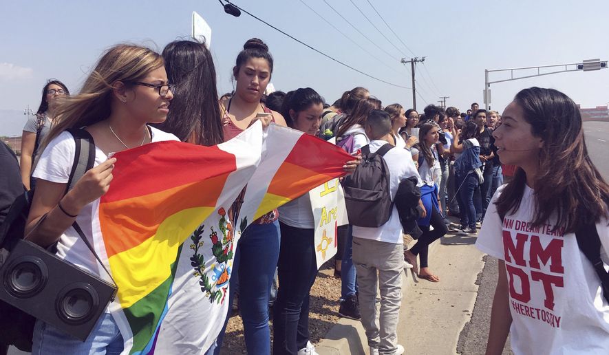 File - In this Sept. 5, 2017 file photo, Albuquerque High School students rally outside of campus on in Albuquerque, N.M., after walking out of class to protest the Trump's administration's decision to end Obama-era immigrant protections. The U.S. Justice Department is including New Mexico's most populous county in an effort to pressure cities to cooperate with federal immigration authorities. Bernalillo County was one of roughly two dozen jurisdictions to receive warning letters Wednesday, Jan. 24, 2018, from the Justice Department. (AP Photo/Russell Contreras, File)