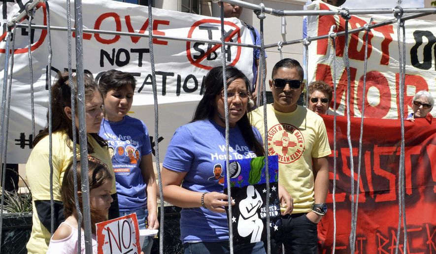 FILE - In this May 1, 2017 file photo, immigrant rights advocates speak out against immigration policies of President Donald Trump while placing themselves in mock detention in Albuquerque, N.M., to mark May Day. The U.S. Justice Department is including New Mexico's most populous county in an effort to pressure cities to cooperate with federal immigration authorities. Bernalillo County was one of roughly two dozen jurisdictions to receive warning letters Wednesday, Jan. 24, 2018, from the Justice Department. (AP Photo/Russell Contreras, File)